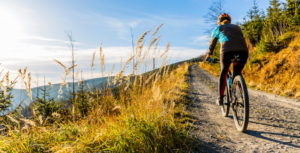 Eine Frau fährt auf dem Mountainbike durch eine Berglandschaft.