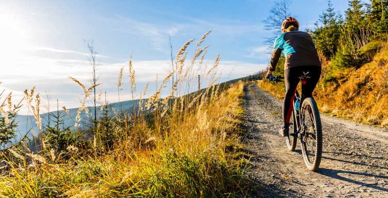 Eine Frau fährt auf dem Mountainbike durch eine Berglandschaft.