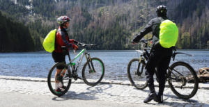 Zwei männliche Mountainbiker stehen mit ihren Rädern an einem See.