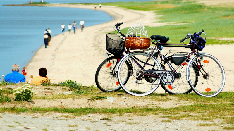 Zwei ältere Fahrräder, abgestellt am Rand eines Sandstrands.