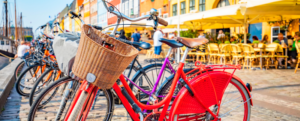 Verschieden farbige Fahrräder stehen im Radständer in einer Stadt.
