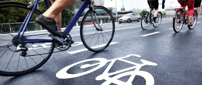 Teilansicht vpn drei Fahrradfahrern auf einer asphaltierten Straße.