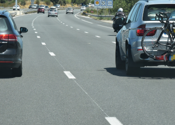 Ein Auto fährt mit einem Fahrrad am Heckträger auf der Autobahn.