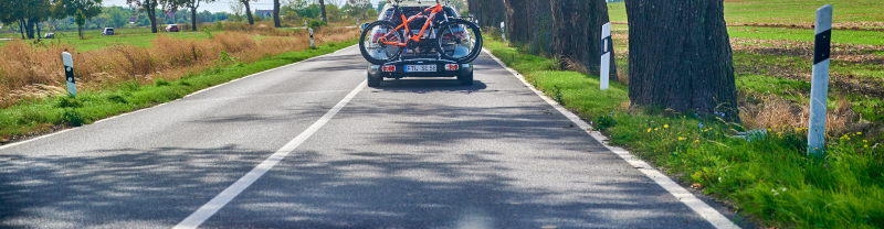 Ein Auto mit Fahrradträger auf einer Landstraße.