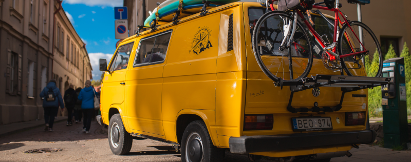 Ein gelber VW Bus, an dem ein Fahrradträger befestigt ist.