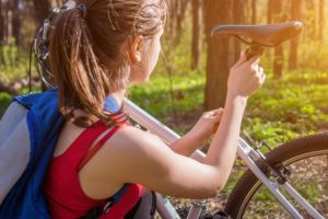 Fahrrad einer jungen Frau die die Höhe des Sattels einstellt