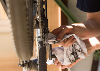 Mann putzt und repariert Kette seines Rades